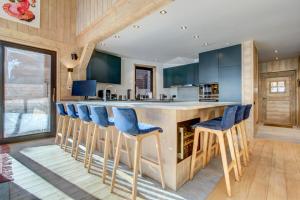 a kitchen with a large island with blue bar stools at Chalet Nosefosa - Magnifique chalet neuf avec piscine intérieure, pour 10 personnes in Morzine