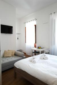 a white bedroom with a bed and a couch at I'MC IoAMoCagliari in Cagliari