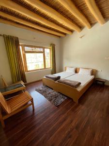 um quarto com uma cama, uma cadeira e uma janela em Chakzot garden house em Leh