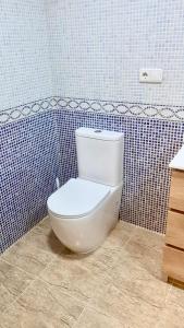 a bathroom with a white toilet in a blue tiled wall at RoNi RoOms in Salou