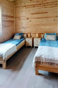 two beds in a room with wooden walls at Niemirowska Osada in Niemirów