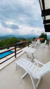 einen Balkon mit Stühlen, einem Tisch und einem Pool in der Unterkunft Villa Sunny Side Skopje in Dolno Solnje