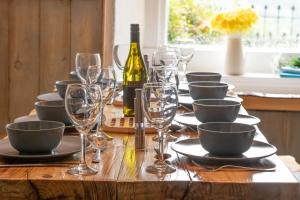 a wooden table with wine glasses and wine bottles at Farmhouse & exclusive outdoor heated pool in Bryn-crug