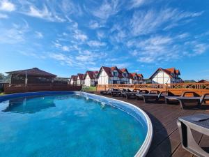 a large swimming pool with chairs and houses at Osada Słowińska in Łeba
