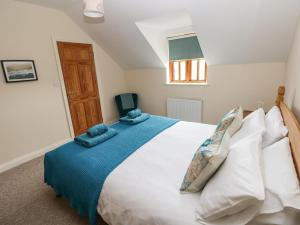 ein Schlafzimmer mit einem großen weißen Bett mit blauer Bettwäsche in der Unterkunft Ty Rhosyn in Haverfordwest