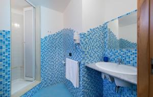 a blue tiled bathroom with a sink and a tub at Angolo Arancio Bed & Breakfast in San Vito lo Capo