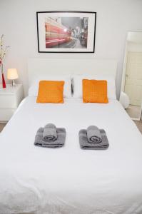 Un dormitorio con una cama blanca con toallas. en 33SM Dreams Unlimited Serviced Accommodation- Staines - Heathrow, en Stanwell