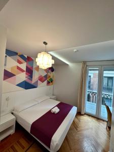 a bedroom with a bed with a colorful painting on the wall at Hostal Abadia Madrid in Madrid