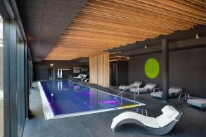 uma piscina num edifício com cadeiras brancas em Black Forest Lodge em Feldberg