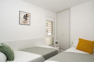 ein weißes Zimmer mit zwei Betten und einem Fenster in der Unterkunft Apartment Bitacora FULLY RENOVATED 2023 in Lloret de Mar