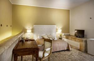 a bedroom with a bed and a desk and a television at Villa Principe Di Belmonte in Ispica