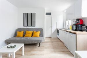 a living room with a gray couch with yellow pillows at NidAudonnien in Saint-Ouen