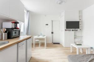 cocina con armarios blancos, mesa y TV en NidAudonnien, en Saint-Ouen