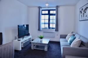 ein Wohnzimmer mit einem Sofa und einem TV in der Unterkunft Nottingham Brand New 1BR Apt w/ Full Kitchen City in Nottingham