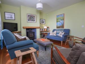 a living room with blue chairs and a tv at Warren Cottage in Stoke Fleming