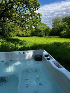 a bath tub filled with water in a field at Lynbrook Cabin and Hot Tub, New Forest in Ringwood
