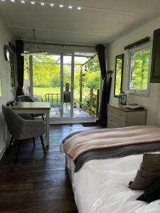 a bedroom with a bed and a desk and a table at Lynbrook Cabin and Hot Tub, New Forest in Ringwood