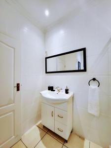 a white bathroom with a sink and a mirror at 136 on 4th in Johannesburg