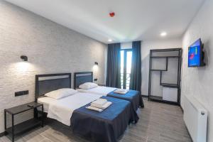 a hotel room with two beds and a tv at Hotel West Way in Kutaisi