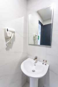 a white bathroom with a sink and a mirror at Hotel West Way in Kutaisi
