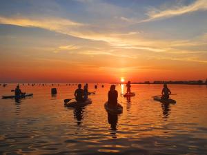 eine Gruppe von Menschen, die bei Sonnenuntergang auf Kajaks im Wasser sitzen in der Unterkunft Bed & Brasserie Het Kosthuys in Sint Maartensdijk