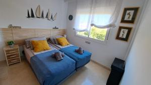 een slaapkamer met 2 bedden met blauwe lakens en een raam bij Sunny holiday Apartment Miraflores in Sitio de Calahonda