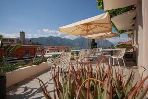 balkon z krzesłami, parasolem i górami w obiekcie Hotel Peler w mieście Malcesine