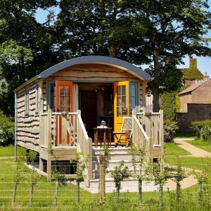 a small cabin in a yard with a fence at Hornington Manor Luxury Shepherd Huts in York
