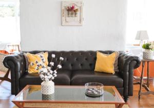 a living room with a black couch with yellow pillows at Hotel Baluma Porto Petro in Portopetro