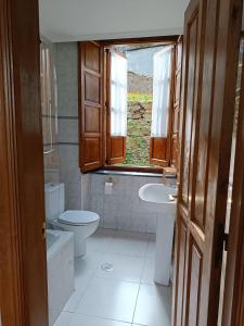 een badkamer met een toilet, een wastafel en een raam bij Apartamentos Rurales San Esteban de los Buitres - Illano 