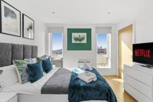 マンチェスターにあるStunning 3-Bedroom Flat with Parkingのベッドルーム(青い枕とテレビ付)