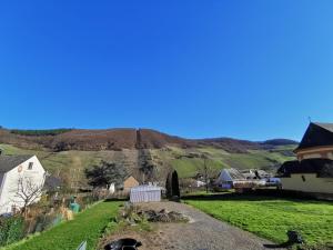 una vista de una granja con una colina en el fondo en Ferienwohnung Zum Moselfischer en Trittenheim