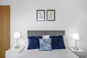 a white bed with blue pillows and two lamps at Stunning 3-Bedroom Flat with Parking in Manchester