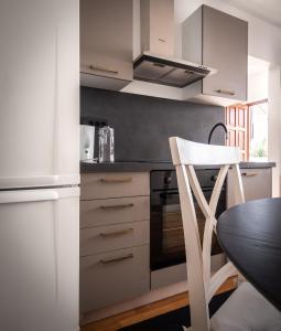 a kitchen with white cabinets and a table and a chair at Apartman Pergola in Betina +12 photos