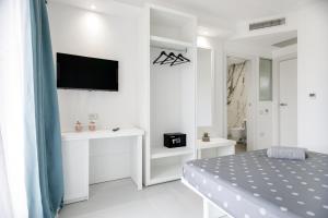 1 dormitorio blanco con 1 cama y TV en la pared en crabonaxa suites en Villasimius