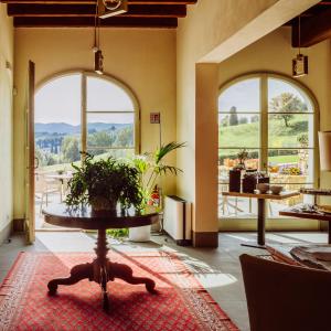 Cette chambre dispose de deux grandes fenêtres et d'une table avec une plante. dans l'établissement Resort 37, à Rignano sullʼArno