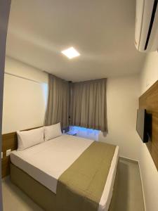 een slaapkamer met een bed en een raam met een televisie bij Edifício Promenade II Apt 404-Mandi Hospitalidade in Maceió