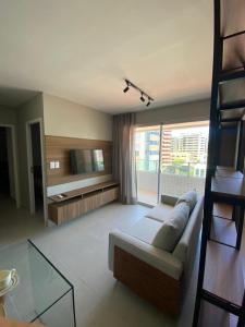 een woonkamer met een bank en een televisie bij Edifício Promenade II Apt 404-Mandi Hospitalidade in Maceió