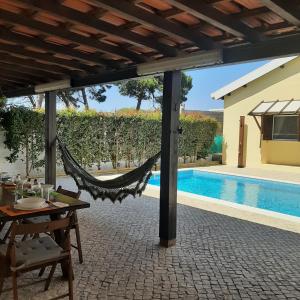 uma rede de descanso num pátio ao lado de uma piscina em casa do vale - Lagoa de Albufeira em Lagoa de Albufeira