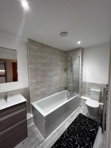 a bathroom with a tub and a toilet and a sink at Cosy 2Bed penthouse,Salford, MCR in Manchester