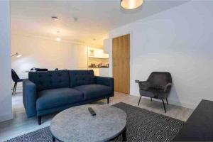 a living room with a blue couch and a chair at Cosy 2Bed penthouse,Salford, MCR in Manchester