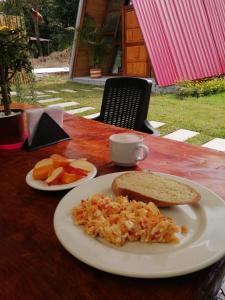 einen Tisch mit einem Teller Essen, einem Sandwich und Obst in der Unterkunft CABAÑAS ALPINA in San Agustín