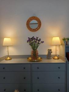 uma cómoda com duas lâmpadas e um vaso com flores em Dom Apartment Luxury em Cagliari