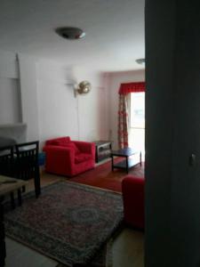 a living room with a red couch and a table at شاليه بقرية كورنادو السخنه in Ain Sokhna