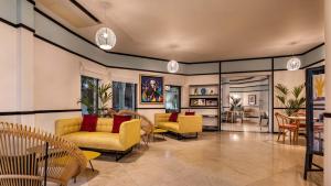 ein Wohnzimmer mit gelben Stühlen und Tischen in der Unterkunft The Magnolia Hotel in Quinta do Lago
