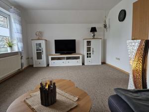 een woonkamer met een tv en een tafel bij Ferienwohnung Renken in Upgant-Schott