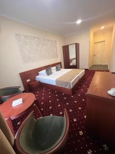 Habitación de hotel con cama y silla en Grand Fortune Hotel en Ereván