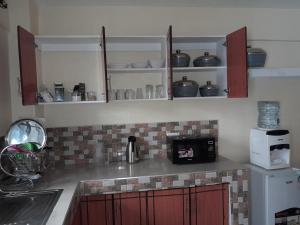 a kitchen with red cabinets and a counter with a microwave at Milimani Nanyuki in Nanyuki