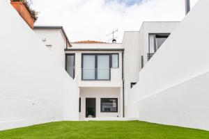 een wit huis met grote ramen en groen gras bij Casa da Granja in Aveiro