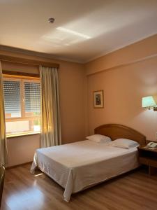 a bedroom with a bed and a window at Grande Hotel Dom Dinis in Mirandela